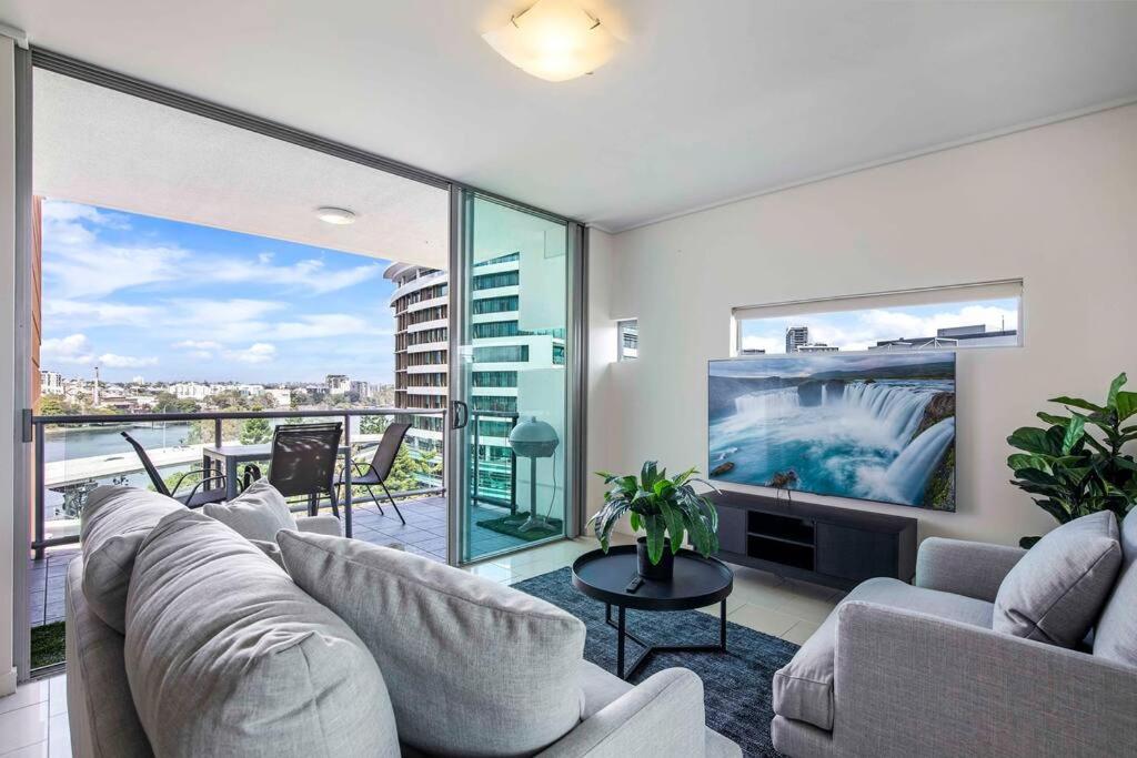 a living room with a couch and a tv at Stadium Vue, 3Bd,Riverview Pool, 300m to S/Stadium in Brisbane