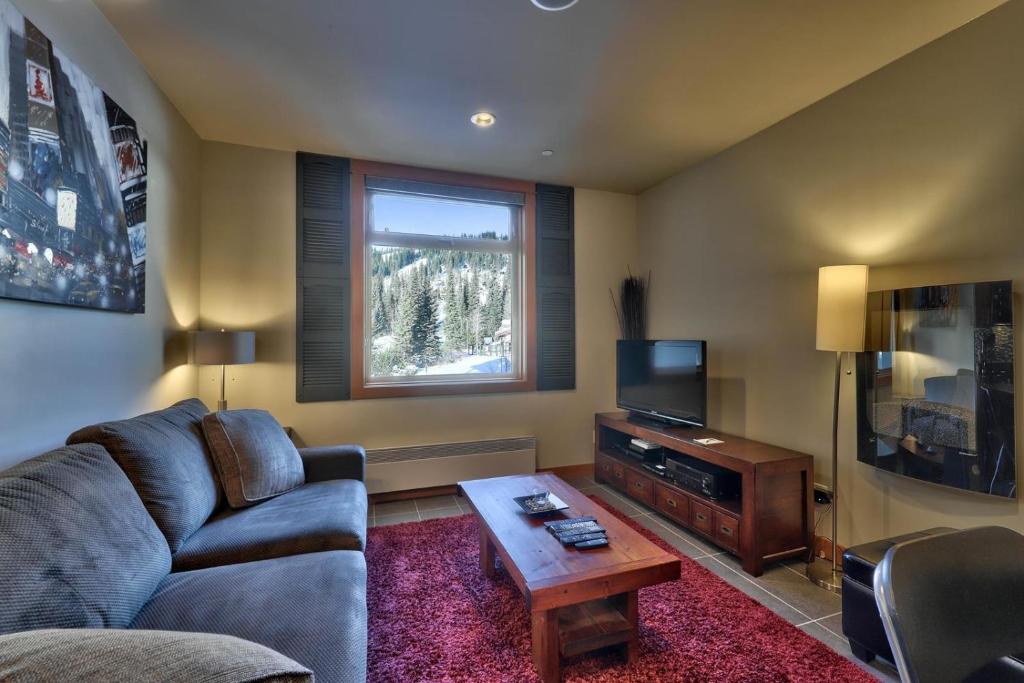 a living room with a couch and a television at Kookaburra Lodge #202 By Bear Country in Sun Peaks
