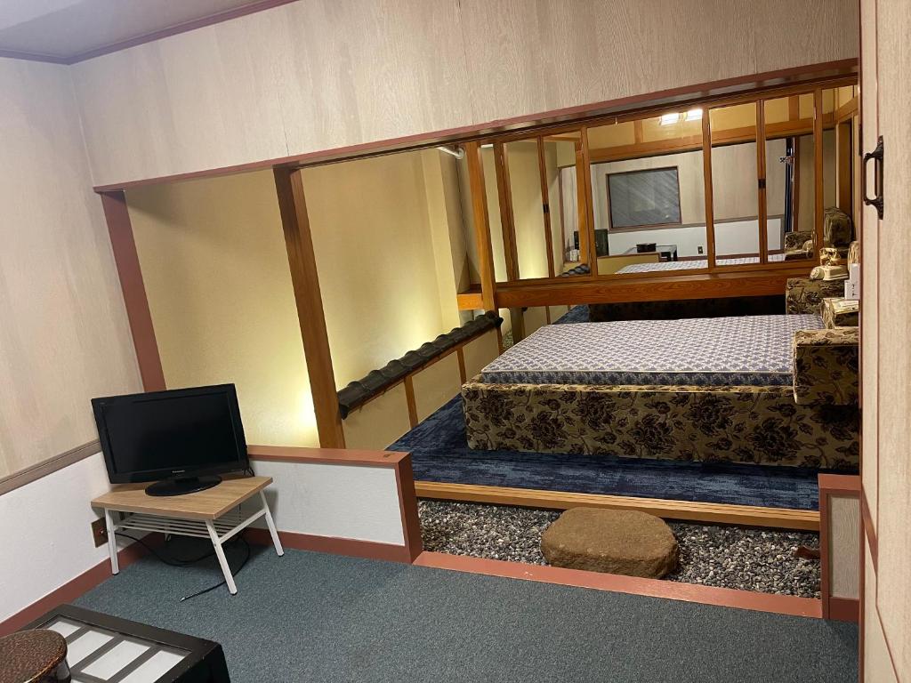 a small room with two beds and a television at ホテルあけぼの in Gamagōri