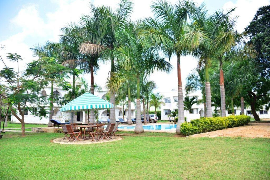 - une table de pique-nique dans un parc avec des palmiers et une piscine dans l'établissement Deluxe Studio Apartment - Royal Palms - Mtwapa, à Shimo la Tewa
