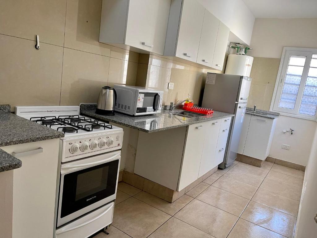 a kitchen with a white stove and a microwave at Departamento temporal 2 Shopping in Villa Nueva