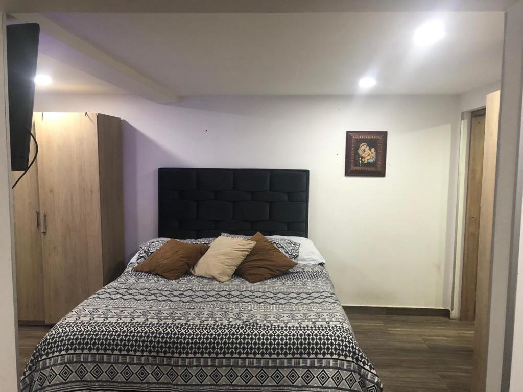 um quarto com uma cama com uma cabeceira preta em Apartaestudio en Bogota. em Bogotá