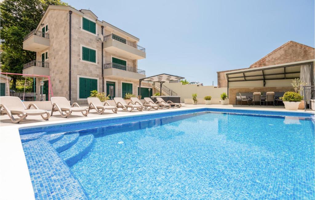 a swimming pool with lounge chairs next to a building at 4 Bedroom Stunning Home In Tucepi in Tučepi