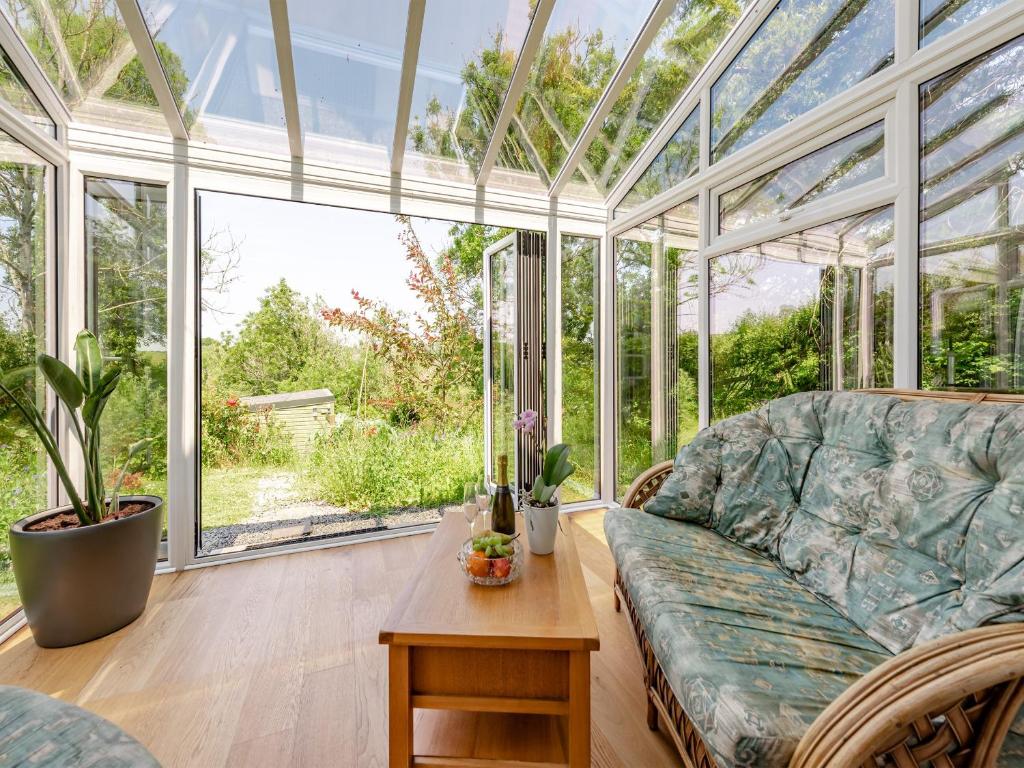 einen Wintergarten mit einem Sofa und einem Tisch in der Unterkunft Tan Y Castell Cottage in Lampeter-Velfrey