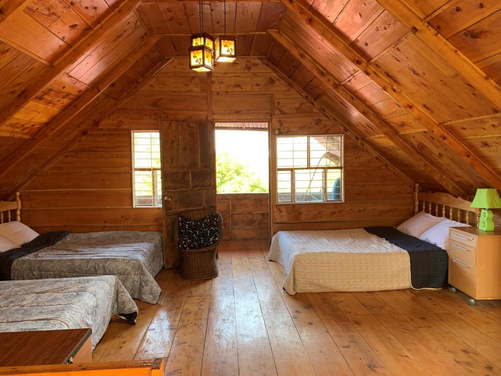 Habitación con 3 camas en una cabaña de madera en Cabaña Mamá Elia en Trinidad