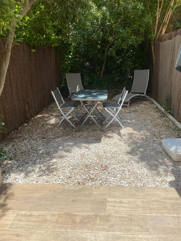 2 chaises et une table dans une cour avec une clôture dans l'établissement Little garden, à Saint-Cyr-sur-Mer