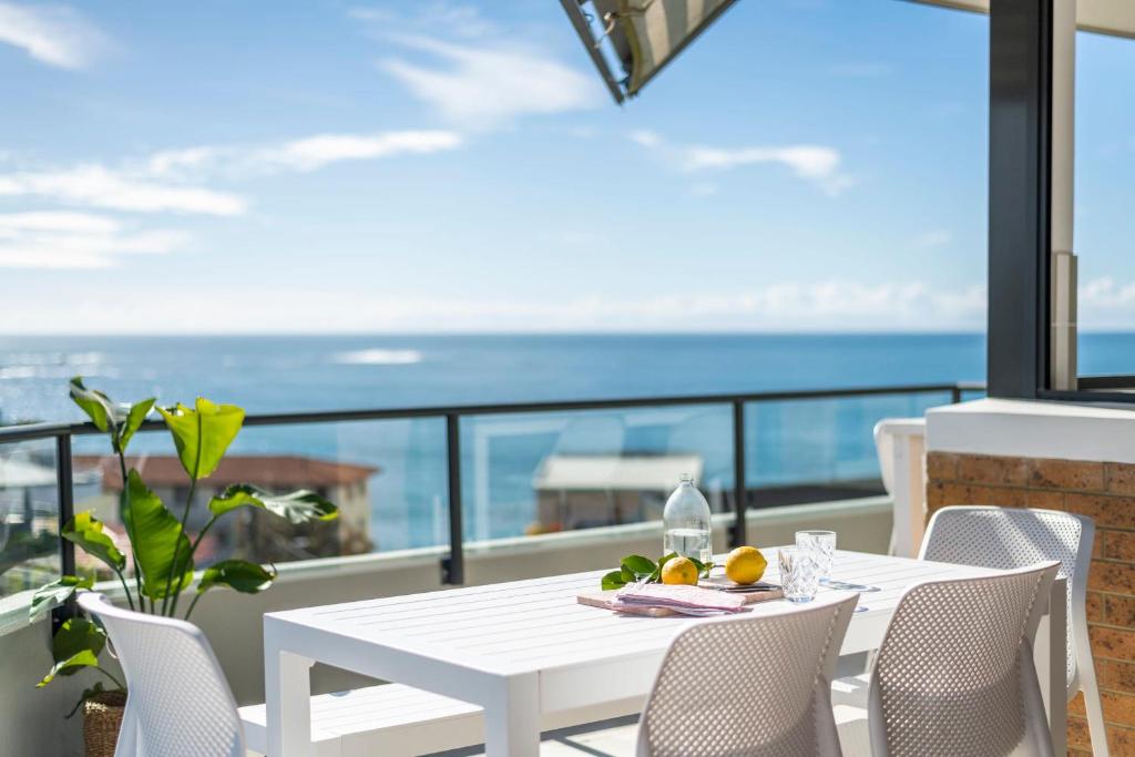 a white table and chairs on a balcony with the ocean at Namanula 7 - oceanstays in Yamba