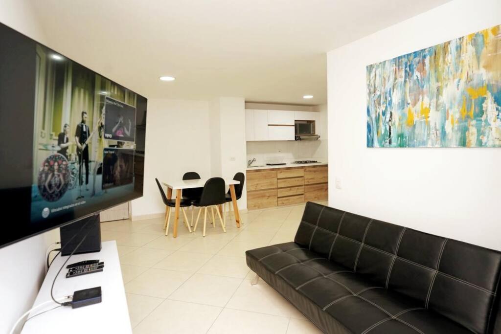 a living room with a black couch and a kitchen at Apartamento Medellin-sabaneta a cuadra del metro in Sabaneta