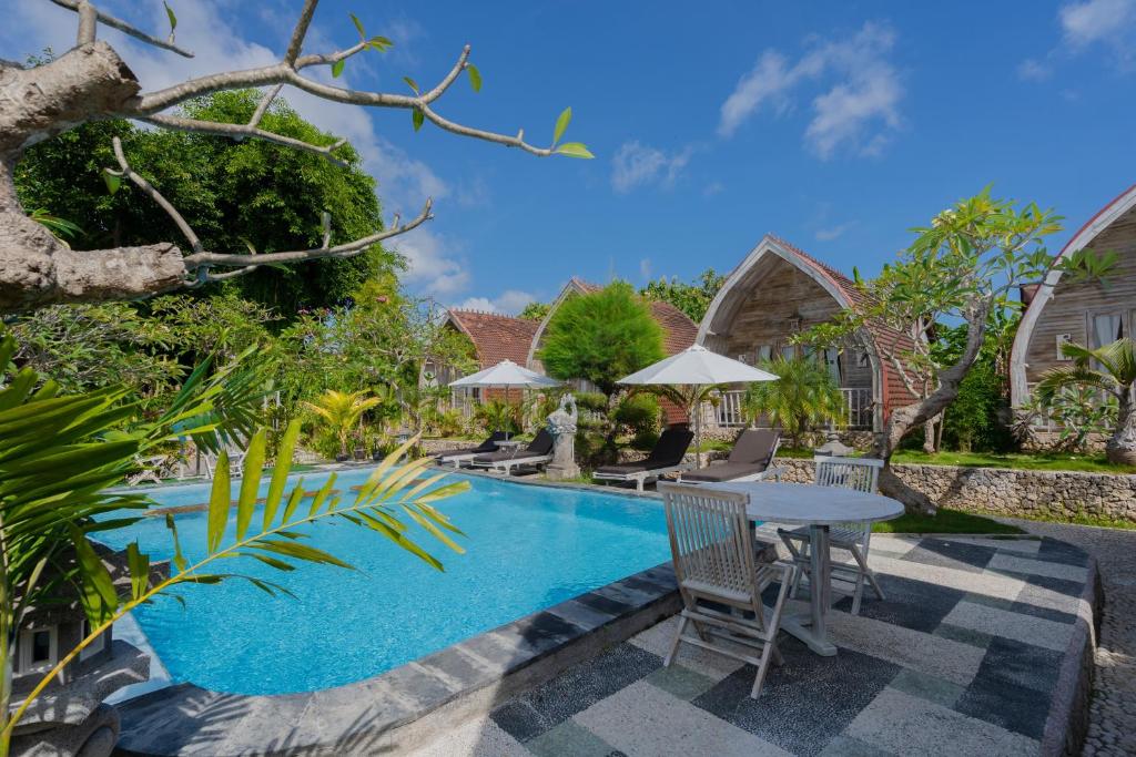 a pool with a table and chairs next to a house at The Mel Huts in Nusa Penida