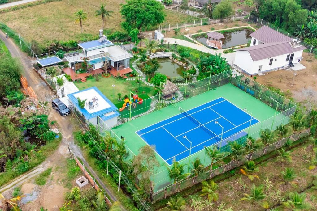 Hana Villa Long An في Long An: اطلالة جوية على منزل مع ملعب تنس