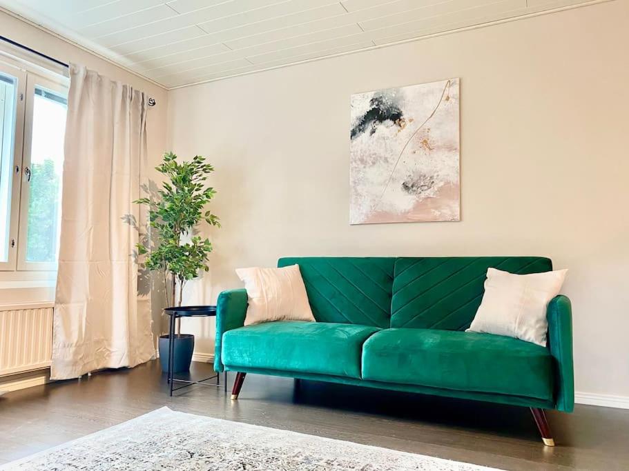 - un canapé vert dans le salon doté d'une fenêtre dans l'établissement Beautiful 2 bedroom & Free parking, à Turku