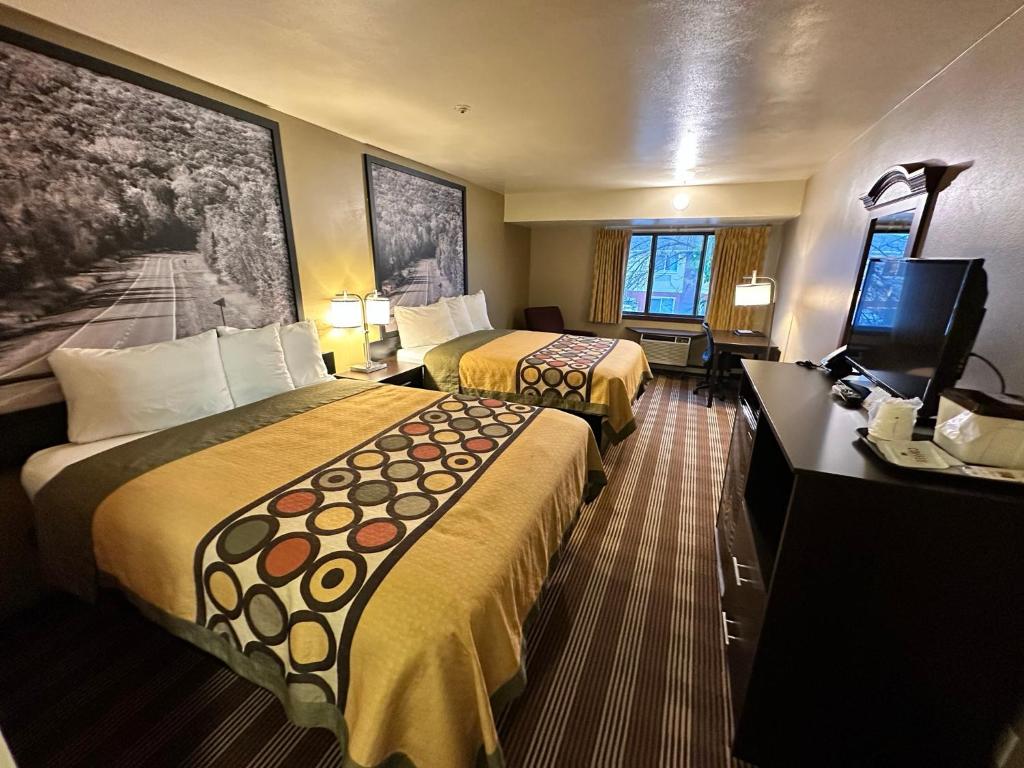 a hotel room with two beds and a flat screen tv at Super 8 by Wyndham Eau Claire WI in Eau Claire