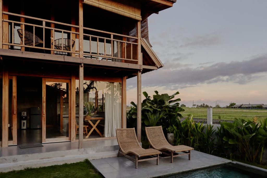 uma casa com duas cadeiras e uma piscina em Bruann residence villa 1, Seseh, Perenenan, amazing sunset view and privacy, 2 bedroom em Munggu