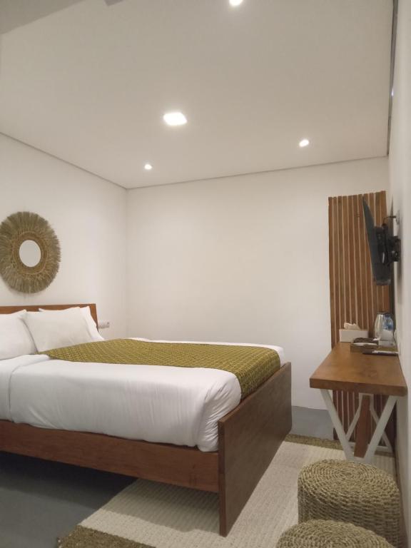 a bedroom with a bed and a table and a chair at Cactus Guest House Borobudur in Borobudur