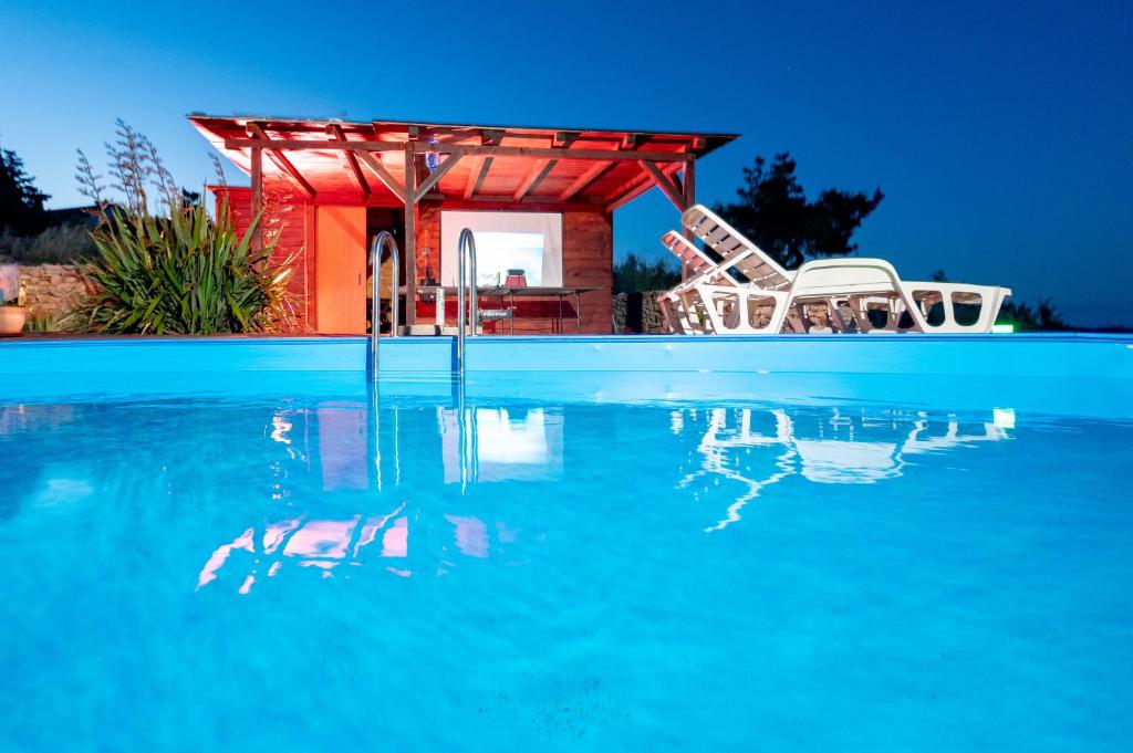 una piscina con una casa e alcune sedie di Apartments Ruža Dragove Dugi otok a Dragove