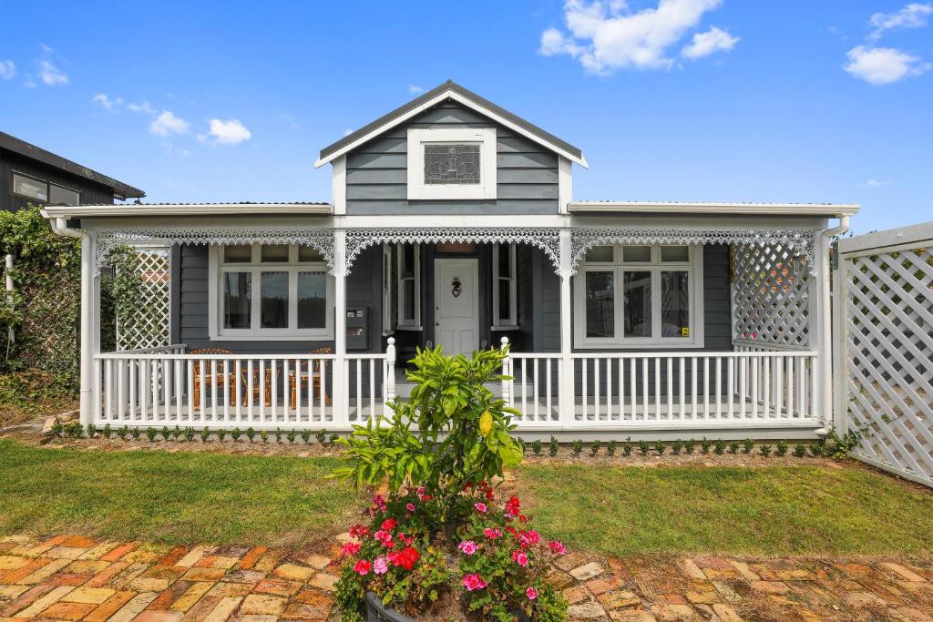 una casa gris con una valla blanca y flores en Central Heritage Villa en Rotorua