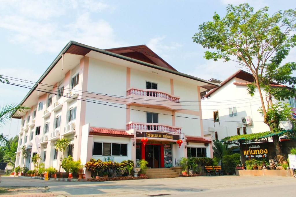 南奔塔恩通酒店的一间大型白色建筑,前面是商店