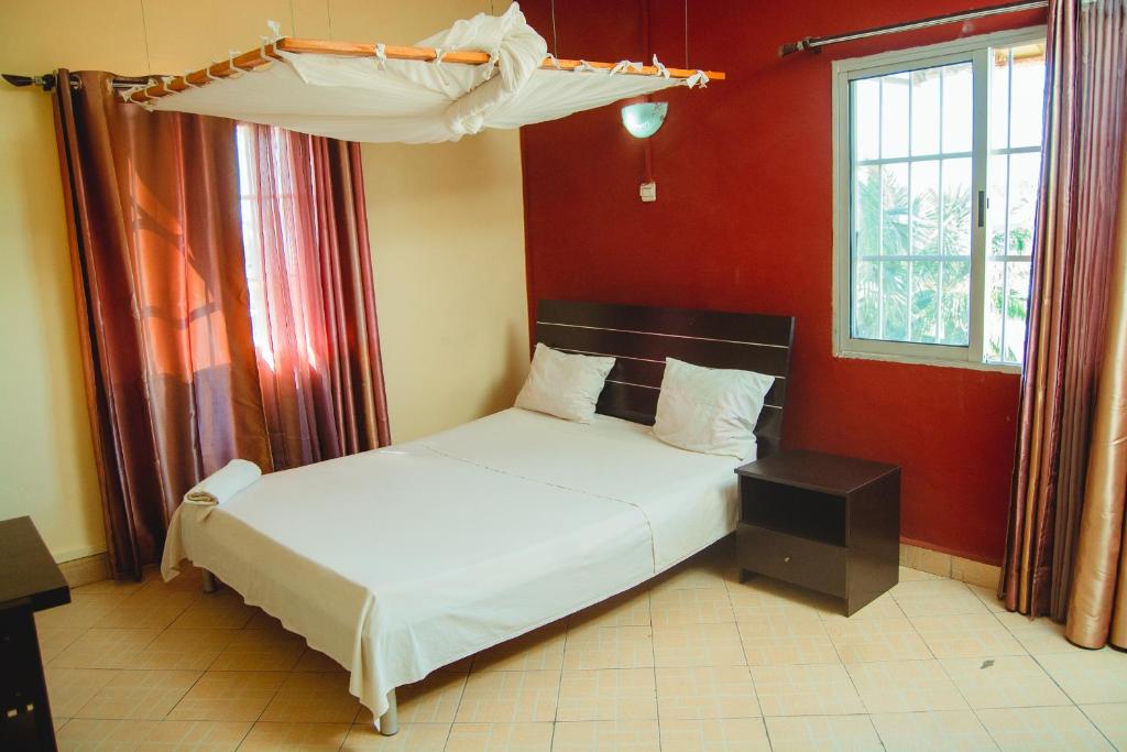 ein Schlafzimmer mit einem Bett in einem roten Zimmer in der Unterkunft Salama Hôtel Majunga in Mahajanga