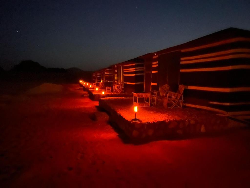 eine Reihe von nachts erleuchteten Lodges in der Unterkunft Salameh's Bedouin Camp in Wadi Rum