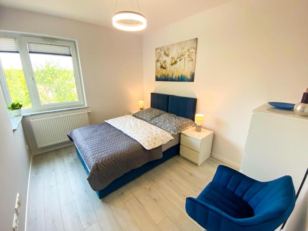 ein Schlafzimmer mit einem Bett und einem blauen Stuhl in der Unterkunft Apartament pod Świerkami in Chojniczki