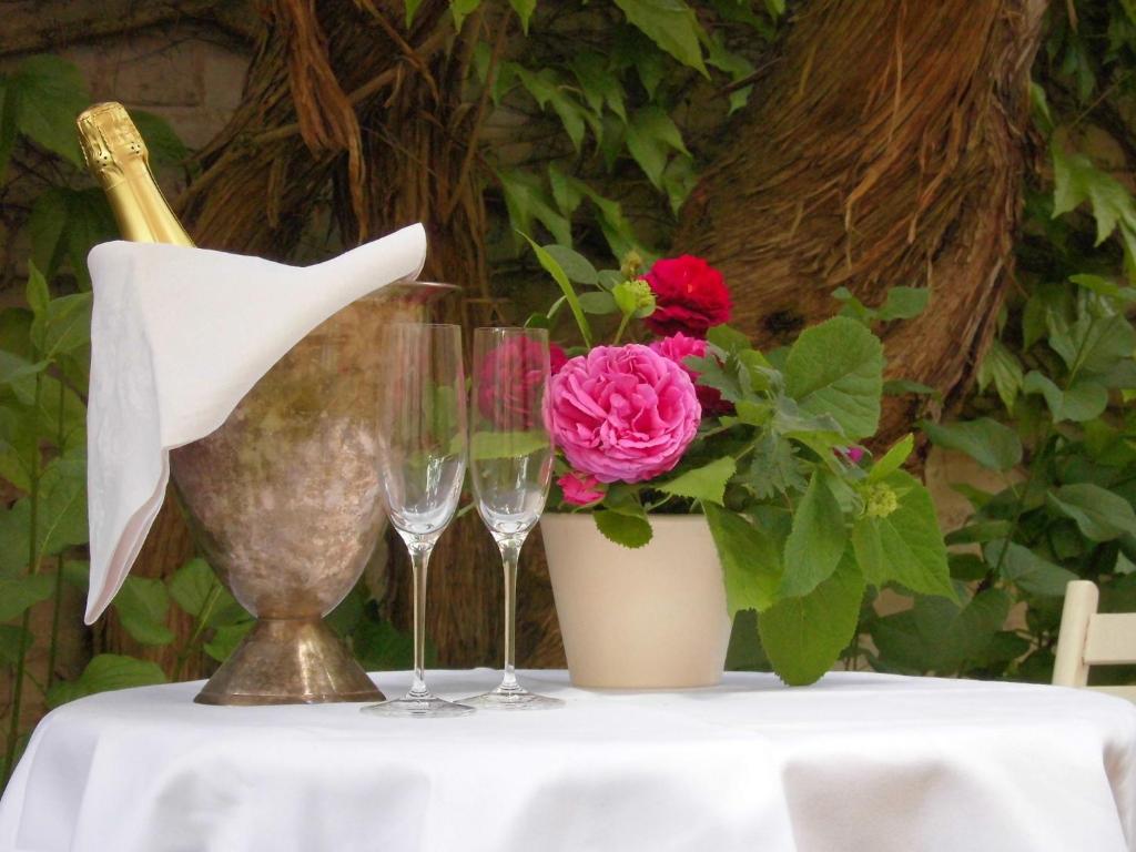 a table with wine glasses and a vase with a flower at SchlossparkFerienwohnungen Rheinsberg in Rheinsberg