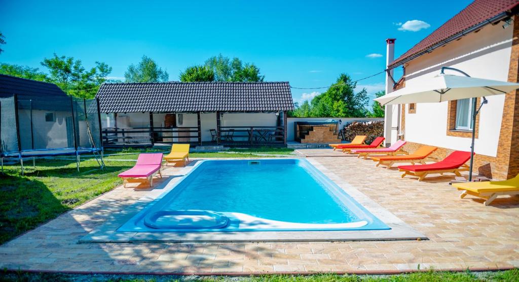 einen Pool mit Stühlen und einem Sonnenschirm in der Unterkunft Avrigelli baby&kids friendly in Avrig