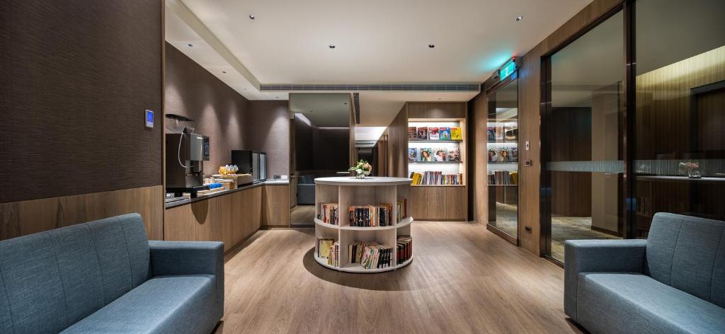 a library with two blue chairs and a table with books at Hotel Intrendy in Taishan