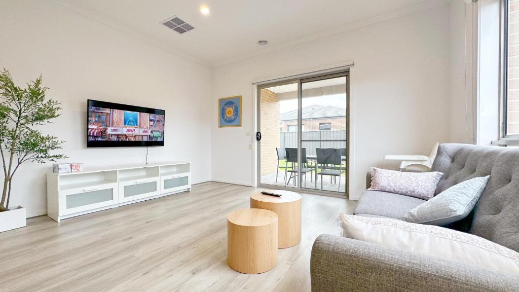 a living room with a couch and a tv at The Grove Townhouse by GoodLive in Tarneit