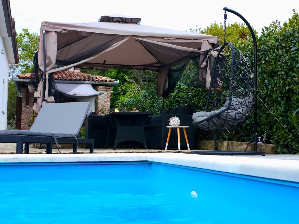 - une piscine avec une balançoire et un parasol dans l'établissement Vila KRISTINA, à Nedeščina