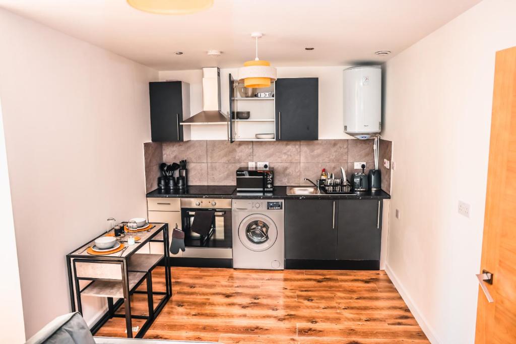 cocina con electrodomésticos en blanco y negro y suelo de madera en Cosy Two Bedroom Apartment en Londres