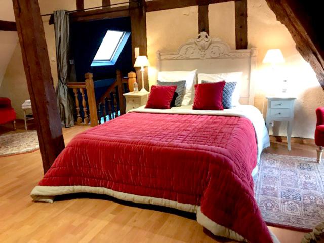 een slaapkamer met een groot bed en een rode deken bij Les Charmes du Perche - Gîte 6 personnes in Vichères