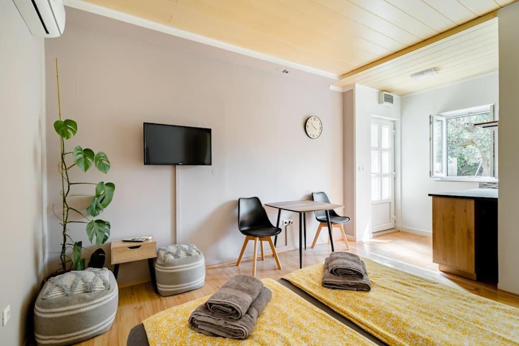 a living room with a table and a tv on the wall at Airport Garden Room in Čilipi