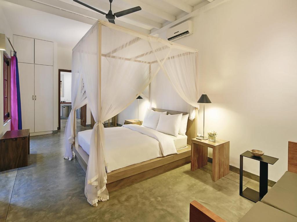 a bedroom with a white bed with a canopy at The Fort Printers in Galle