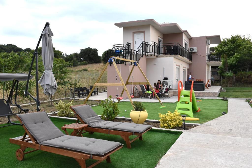 un patio trasero con un parque infantil con sillas y un columpio en Salt and petals, en Samotracia