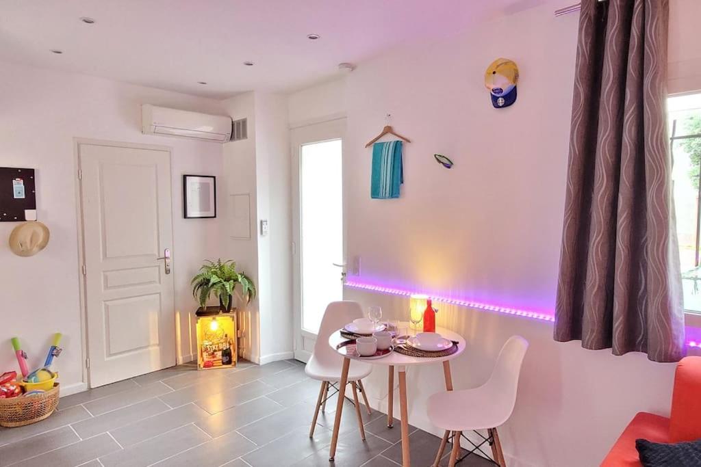 un salon avec une table et une lumière violette dans l'établissement Au petit QG: Apt cosy pour 2 Prs, 200m des plages, à Antibes