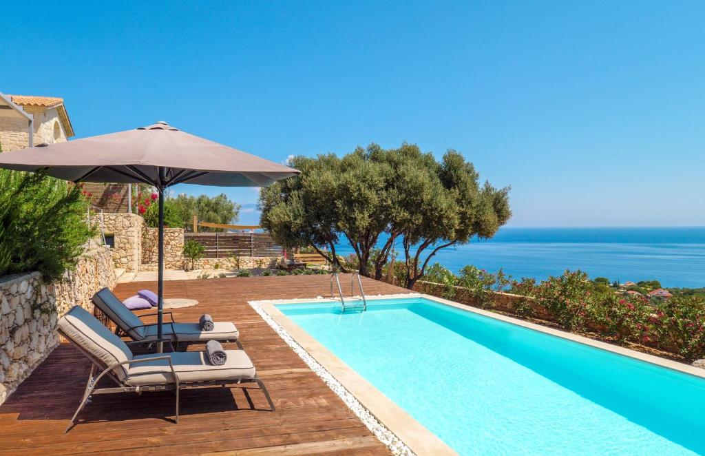 a swimming pool with two chairs and an umbrella next to the ocean at The Yiameli Collection - Yasmi in Skinária
