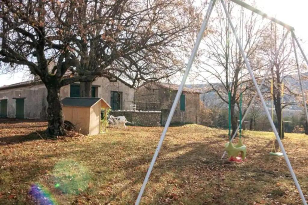 a swing in a yard with a tree and a house at La Bastide De Queyran in La Palud sur Verdon
