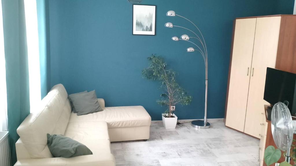 sala de estar con sofá blanco y pared azul en Apartament Leśny, en Lubin