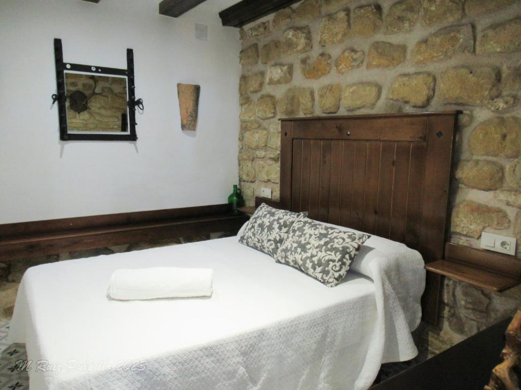 een slaapkamer met een bed en een stenen muur bij La alegria de las cuevas in Rus