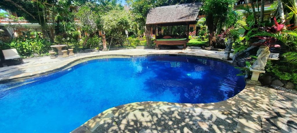 a large pool with blue water in a yard at Rambutan Hotel in Lovina
