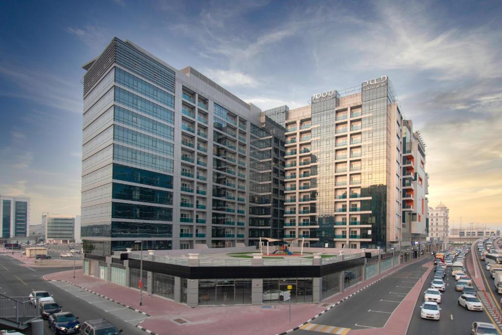 a large building with cars parked in a city at Jood Hotel Apartments in Dubai