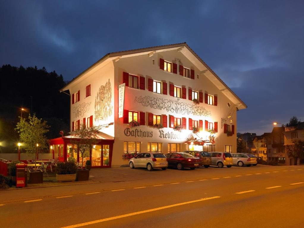 Hotel Rebstock - Self Check-in في Wolhusen: مبنى فيه سيارات تقف امامه ليلا