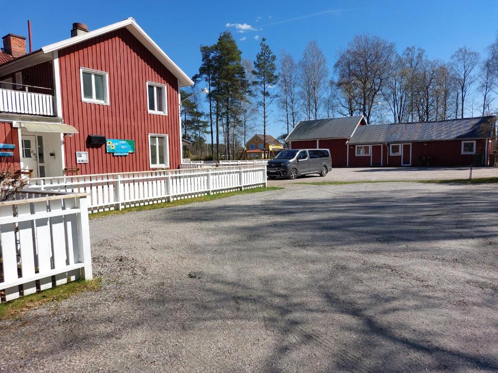 un coche estacionado junto a un granero rojo con una valla blanca en Flora Dekor gästgård, Lenagården en Alingsås