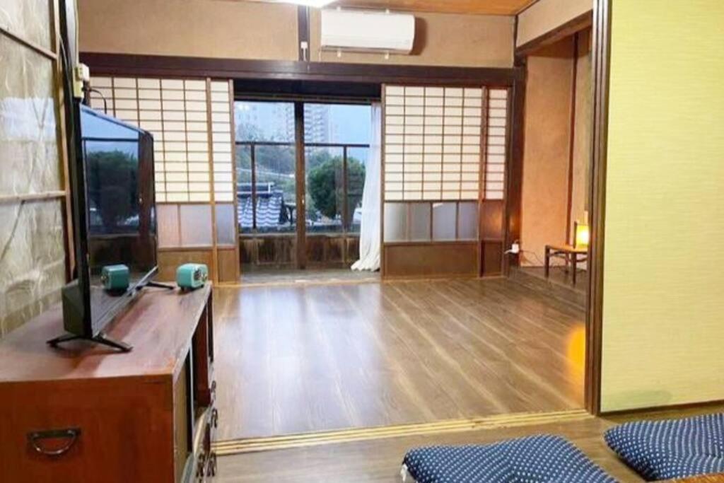 um quarto vazio com uma televisão e um piso de madeira em おとまりどころ下関本町 em Shimonoseki