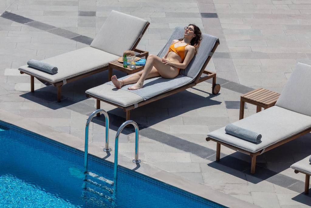 a woman sitting in a chair next to a swimming pool at Doria Hotel Bodrum-City Center in Bitez