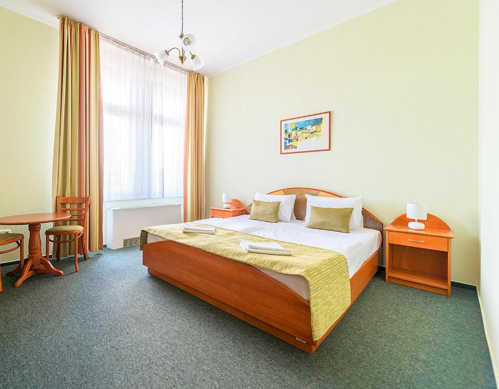 ブダペストにあるバロス シティ ホテル ブダペストのベッドとテーブルが備わるホテルルームです。