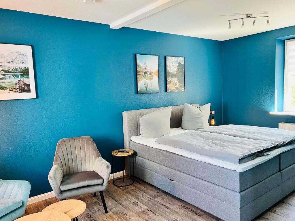 ein blaues Schlafzimmer mit einem Bett und einem Stuhl in der Unterkunft BlueLagoon in Schweinfurt