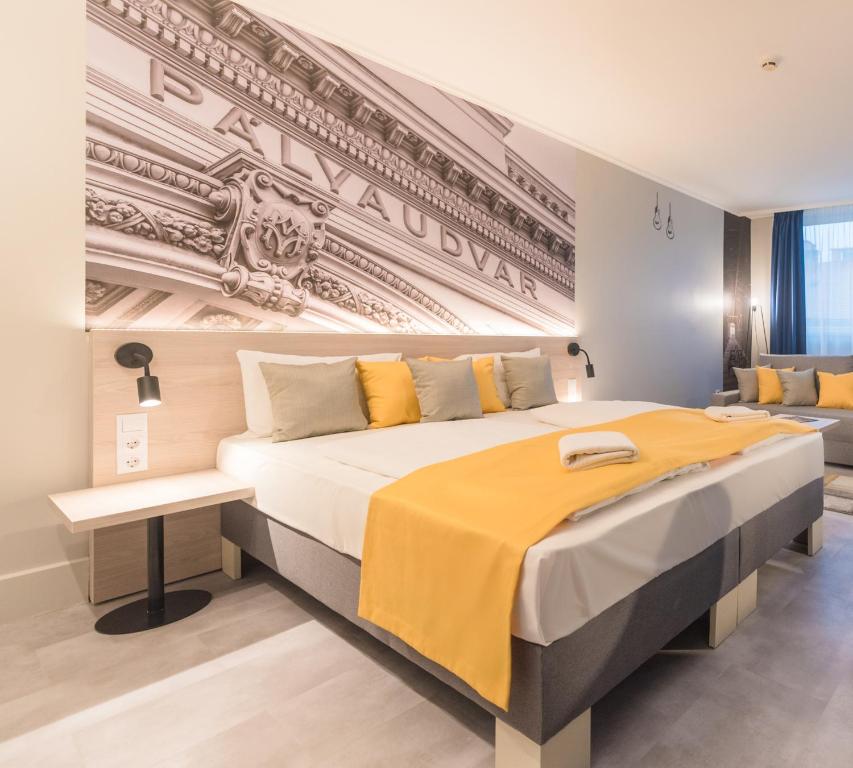 a bedroom with a large bed with a yellow blanket at Impulso Fashion Hotel in Budapest