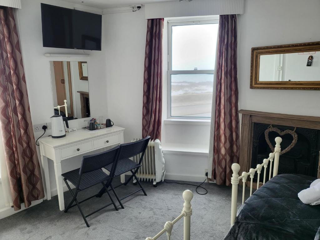 a bedroom with a desk and a bed and a window at St Georges in St Peter Port