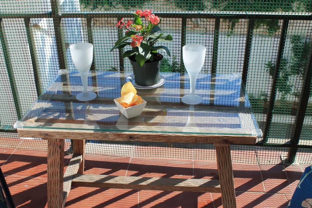een houten tafel met twee glazen en een vaas met bloemen bij Apartamento Carlota beach carihuela in Torremolinos